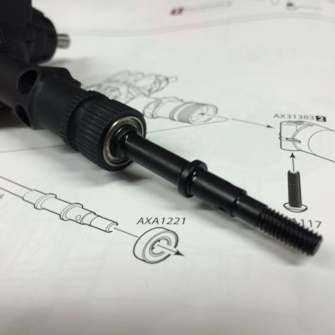 1989 Ford Bronco - Close-up of a black metal drive shaft assembly with bearings, laid over a technical diagram.