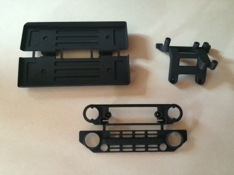 1989 Ford Bronco - Model car parts, including a grille and bumper, are laid out on a light-colored surface.