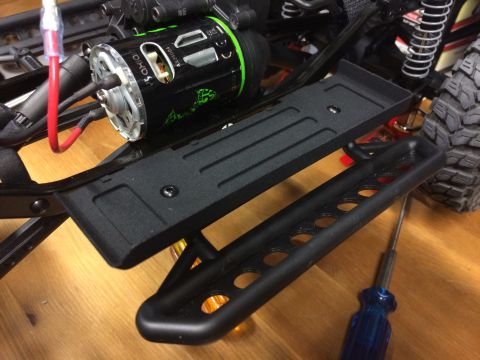 1989 Ford Bronco - Close-up of an RC car chassis, showing the motor and side steps, with a screwdriver nearby.