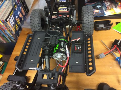 1989 Ford Bronco - Close-up of an RC car chassis, detailing the motor, electronic speed controller, and suspension components.