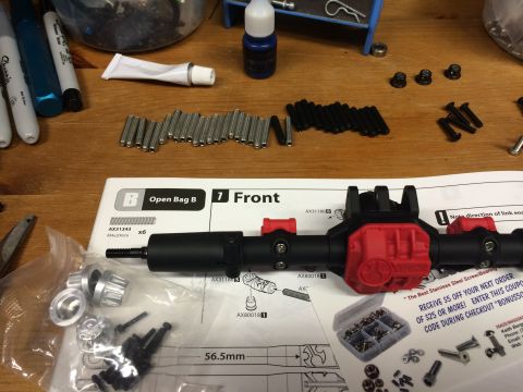 1989 Ford Bronco - RC car axle assembly parts and instructions are spread out on a wooden surface.