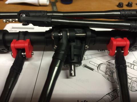 1989 Ford Bronco - Close-up of RC car suspension parts, including linkages and red mounting brackets, laid out on an instruction manual.