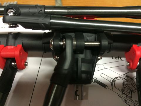 1989 Ford Bronco - Close-up view of black and red suspension parts for an RC car, resting on assembly instructions.