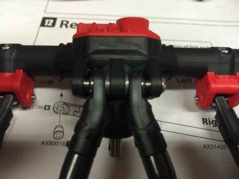 1989 Ford Bronco - Close-up of a black and red RC car suspension component, with assembly instructions visible in the background.