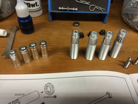 1989 Ford Bronco - Various metal components and a wrench are arranged on a wooden surface next to assembly instructions.