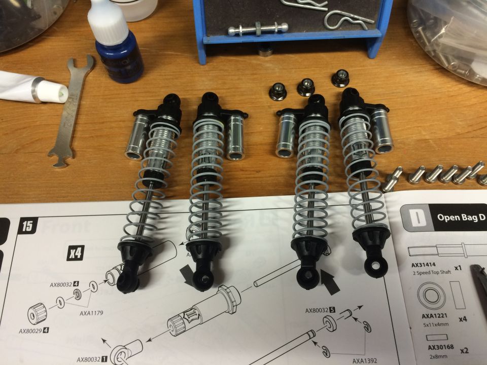 Four RC car shock absorbers with assembly diagram and parts