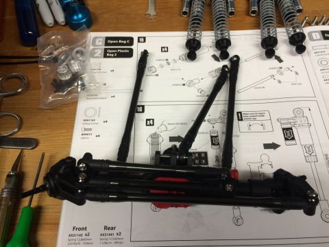 1989 Ford Bronco - RC car suspension components and assembly instructions are laid out on a wooden table.