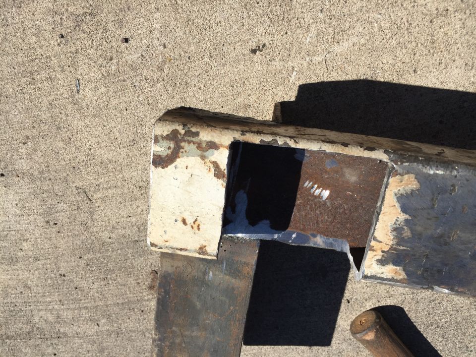 Rusted metal frame part with white paint remnants and visible weld marks