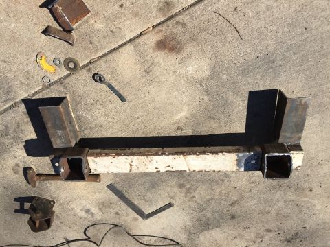 1996 Ford F-150 - A custom trailer hitch assembly lies on concrete, surrounded by tools and metal scraps, suggesting a DIY project.