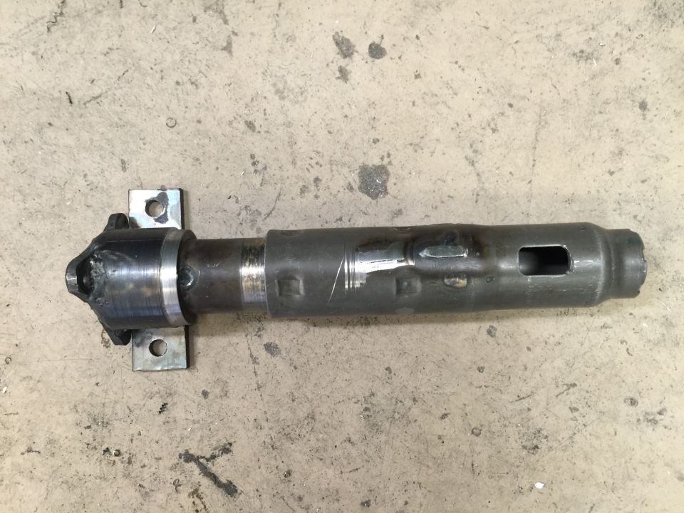Metal driveshaft component with a U-joint and mounting brackets, on a concrete surface