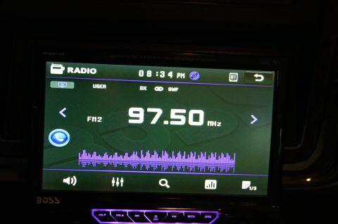 1979 Ford Bronco - The interior of a vehicle shows a modern car stereo display with radio information and an equalizer graphic.