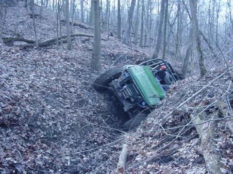 1992 Ford Bronco - Off-road vehicle stuck in a ditch on a wooded hillside.