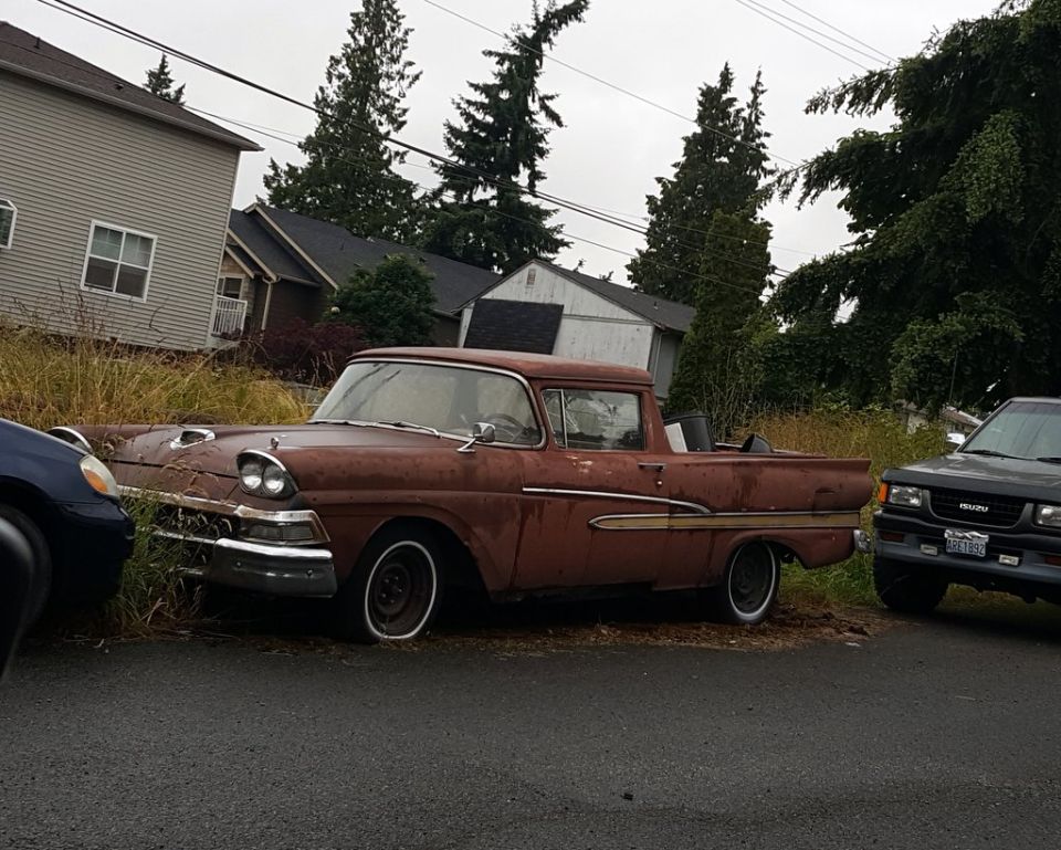 Rusty red 1957 pickup truck parked next to a dark SUV