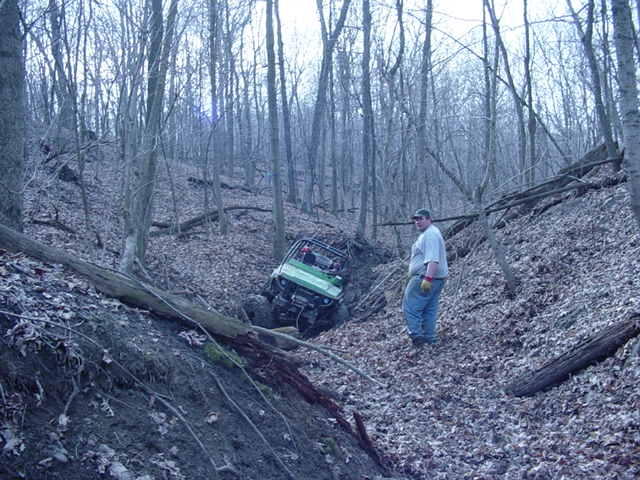 Green off-road vehicle stuck in a wooded ditch