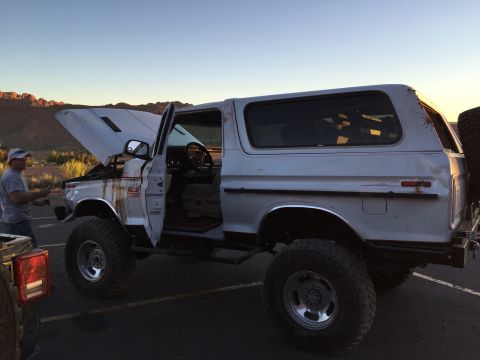 1979 Ford Bronco - A white 1979 Ford Bronco is shown with its hood and driver's door open, parked in an outdoor lot with a man standing nearby.