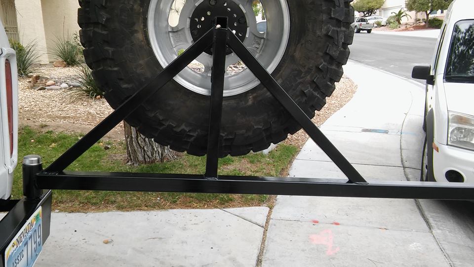 Spare tire carrier mounted on rear bumper, with tire and wheel visible