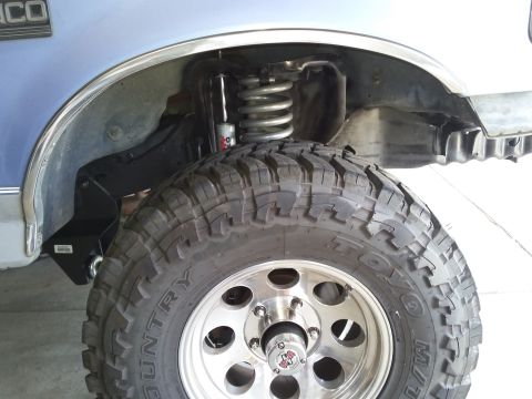 1996 Ford Bronco - Close-up of the suspension and tire assembly on a blue 1996 Ford Bronco.
