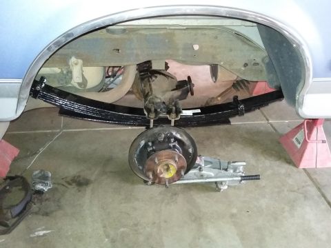 1996 Ford Bronco - The rear suspension of a 1996 Ford Bronco, showing leaf springs and a removed brake drum, is pictured during maintenance.