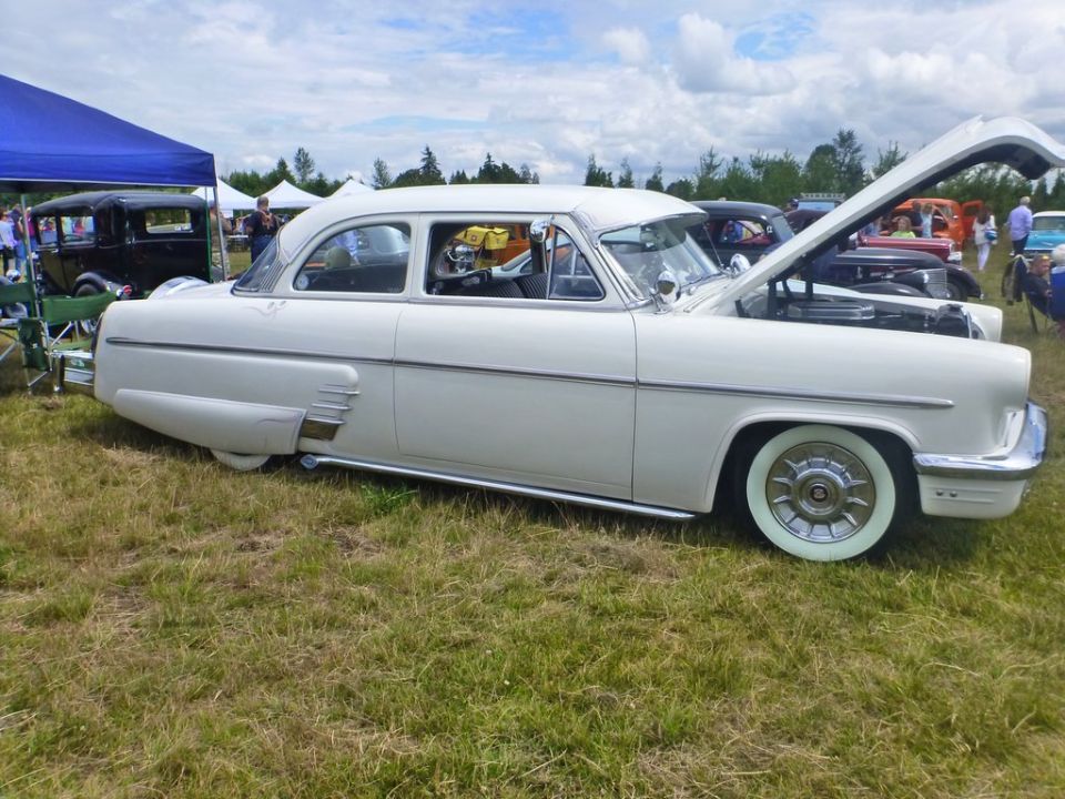 White 1954 Mercury Monterey sedan, hood open, parked on grass