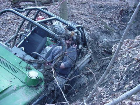 1992 Ford Bronco - An off-road vehicle with a roll cage is stuck deep in a muddy ditch.