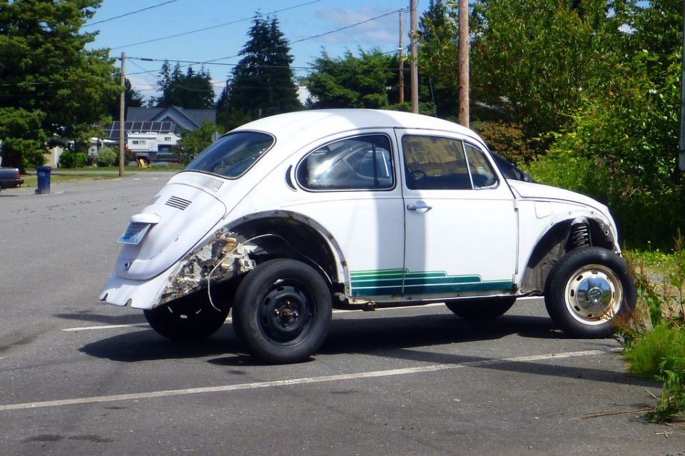White Volkswagen Beetle with green stripes, missing body panels on rear quarter, and mismatched wheels