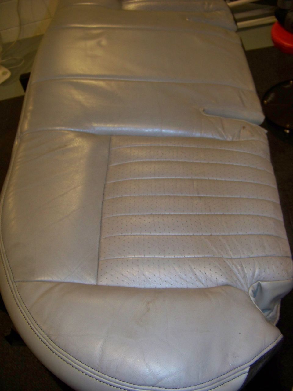 Light gray leather car seat with perforated inserts and horizontal stitching