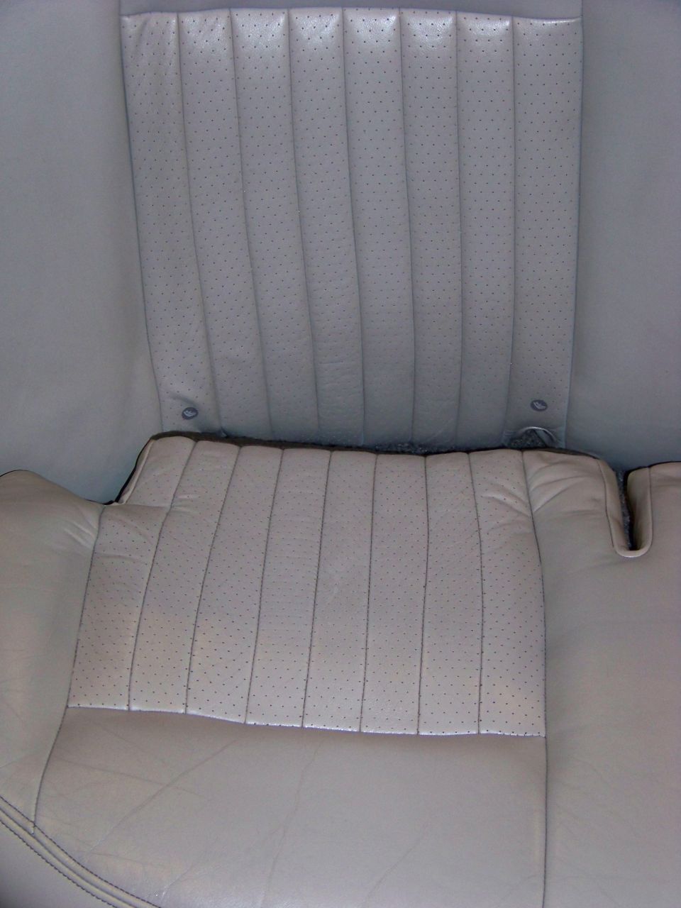 Perforated leather car seats, light tan color, showing vertical stitching detail on the seat back and cushion