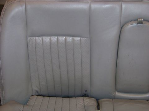 2001 Mercury Grand Marquis - Close-up of a car's rear seat, showing the perforated leather upholstery and armrest.