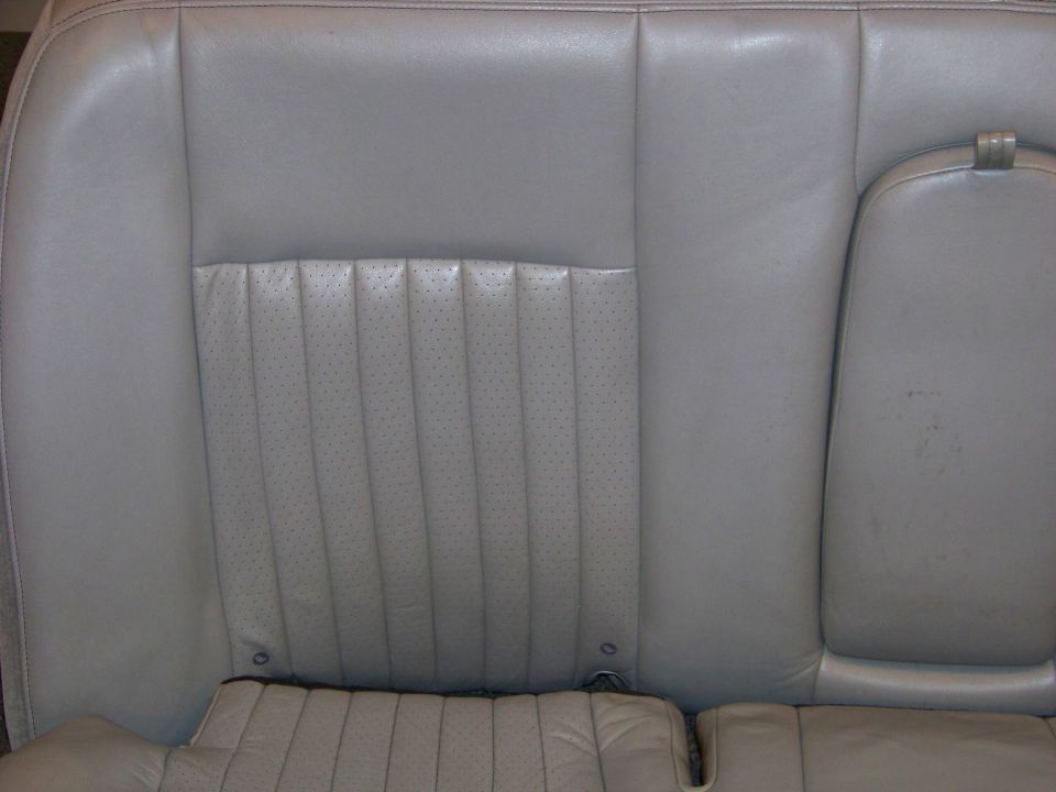 Gray leather car seat interior with perforated inserts and a center armrest