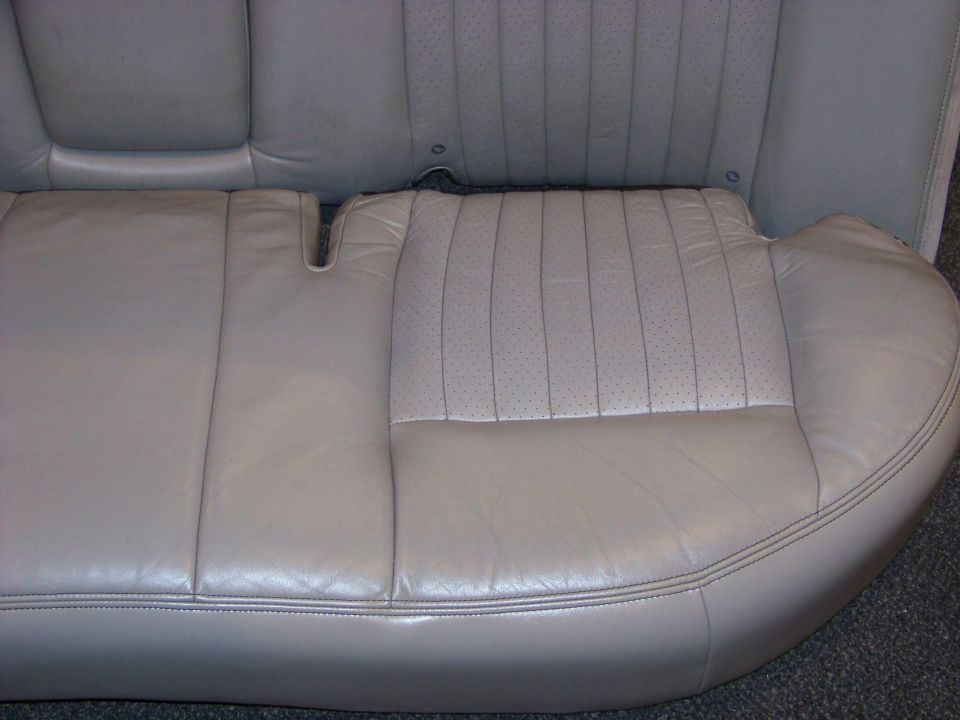 Light tan leather rear car seat with perforated inserts on the right cushion