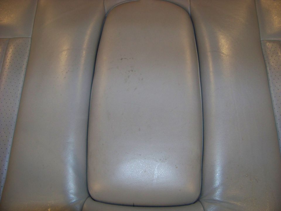 Tan leather rear seat armrest with visible wear marks