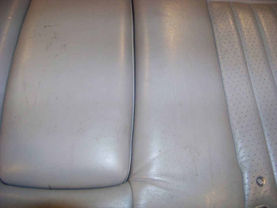 Close-up of light-colored leather car seats, showing stitching and perforated sections