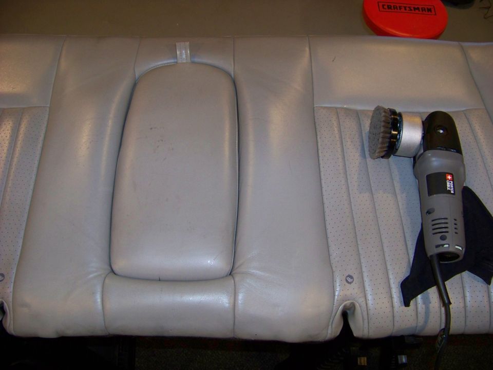 Light gray leather car seat with a center armrest and a polishing tool nearby