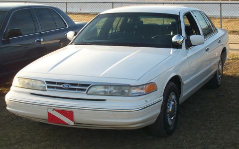 1993 Mercury Grand Marquis - A white 1993 Mercury Grand Marquis sedan is parked next to a dark sedan.