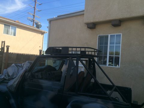 1987 Suzuki Samurai - A modified 1987 Suzuki Samurai is parked in a residential area with a roll cage and roof rack visible.
