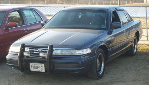 1993 Mercury Grand Marquis - Front view of a dark blue sedan with a push bar, parked next to another sedan.