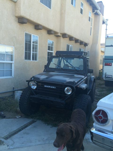 1987 Suzuki Samurai - This 1987 Suzuki Samurai features oversized off-road tires and a roof rack, suggesting it's modified for terrain.