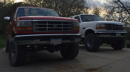 1996 Ford Bronco - Two Ford Broncos, a red one in the foreground and a white one behind it, are parked outdoors.