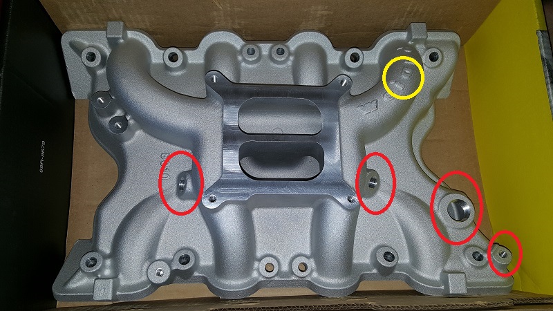 Aftermarket aluminum intake manifold with red and yellow circles highlighting mounting points and vacuum ports