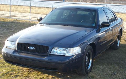 1993 Mercury Grand Marquis - This Ford Crown Victoria features a distinctive black honeycomb grille and a dark blue exterior, parked outdoors on a grassy area.