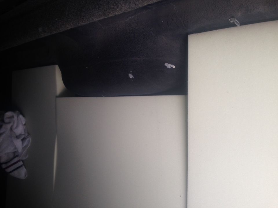 Spare tire in a vehicle's storage area, with some white panels and a cloth
