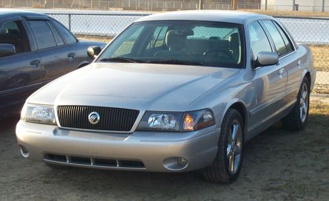 1993 Mercury Grand Marquis - This silver sedan features a distinctive vertical grille and chrome wheels, suggesting a model year around 2003.