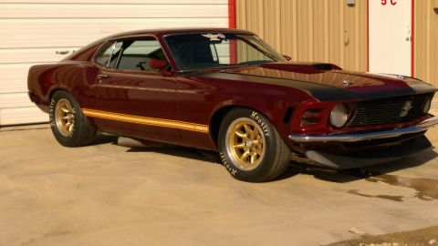 1970 Ford Mustang - This 1970 Ford Mustang features a distinctive maroon paint job with gold racing stripes and a prominent hood scoop.