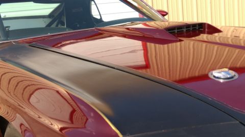 1970 Ford Mustang - The reflection on the car's hood shows a building with vertical siding.