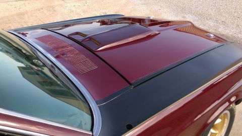 1970 Ford Mustang - Close-up of a maroon 1970 Ford Mustang hood a black stripe and a prominent hood scoop.