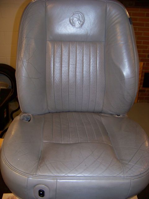 2001 Mercury Grand Marquis - This gray leather car seat, likely from a 2001 Mercury Grand Marquis, displays the brand's emblem and signs of use.