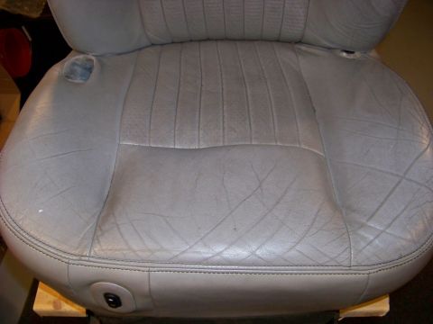 2001 Mercury Grand Marquis - Close-up of a light gray leather car seat, showing stitching detail and signs of wear.