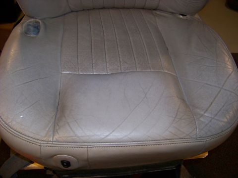 2001 Mercury Grand Marquis - Close-up of a worn gray leather car seat, showing stitching and perforated sections.