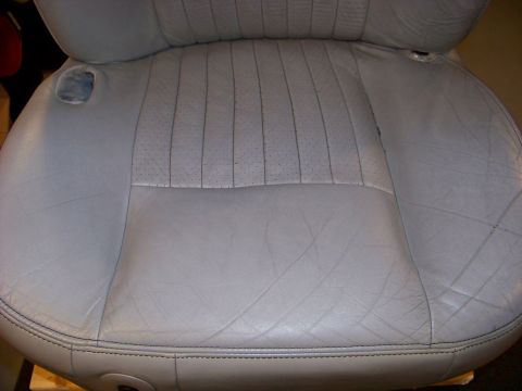 2001 Mercury Grand Marquis - Close-up of a light gray leather car seat, showing its stitching and a small tear on the left side.