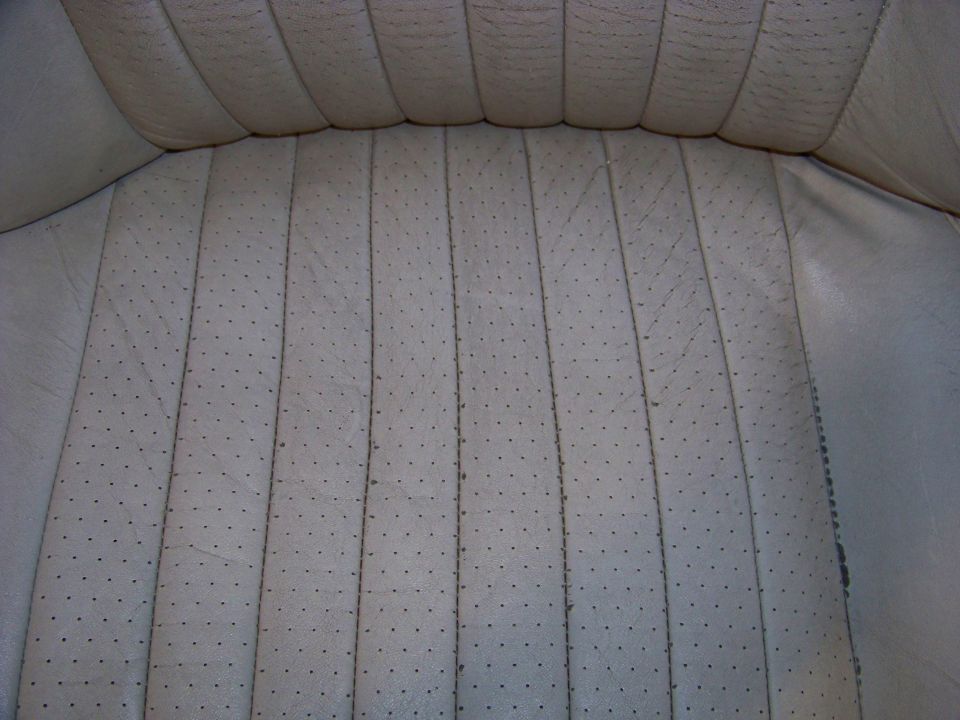 Close-up of light-colored perforated leather seat upholstery with vertical stitching